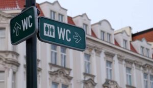 WC sign, logo of public toilets in the street against building background. For female, male. Public toilet sign against building.-cm