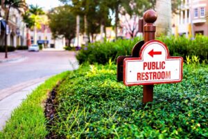 Naples, Florida residential street old town condo building community place with sign direction signpost for public restroom and nobody on road -cm